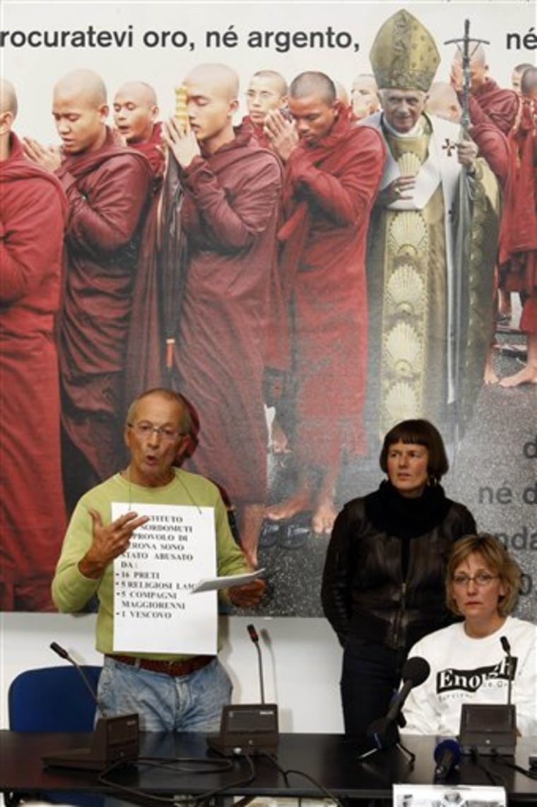 Italian deaf man Gianni Bisioli, left, wears a sign with writing in Italian reading "At Verona's Provolo Institute for the Deaf I was abused by 16 priests, 5 clergymen, 5 older classmates and one bishop," during a press conference in Rome on Sunday. People from a dozen countries who allege they were raped or molested by Catholic priests as children gathered in Rome for a candlelit march on the Vatican intended to let survivors know they're not alone.
